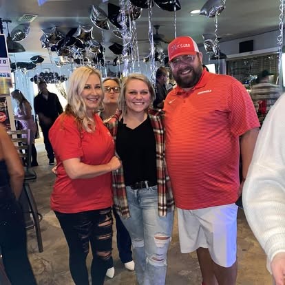 All smiles at the party, arm in arm under the balloons.
