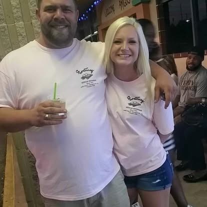Drink in hand and an arm around a friend, all smiles.