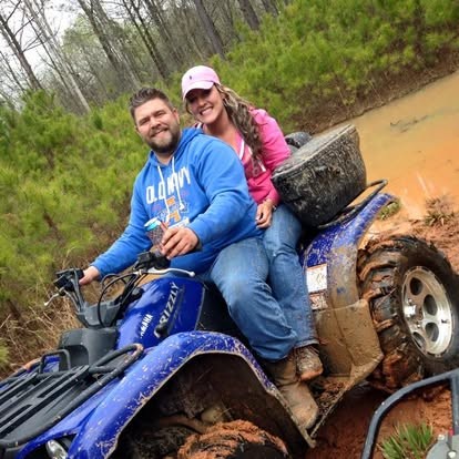Grinning together on a muddy ATV out in the woods.
