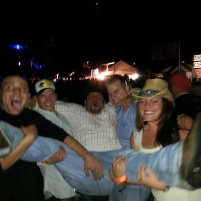 Hoisted up by laughing friends at a bright summer night.