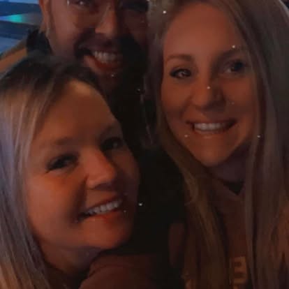 Big grin, tucked between friends for a night-out selfie.